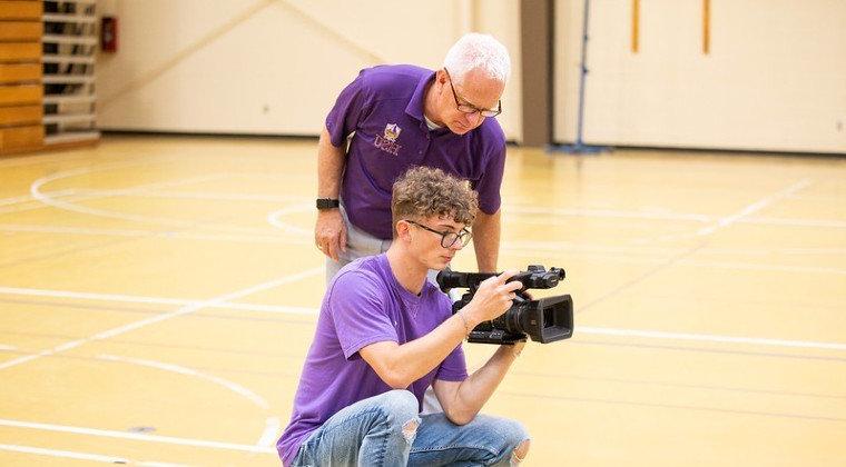 Staff member trains a student worker on camera operation.